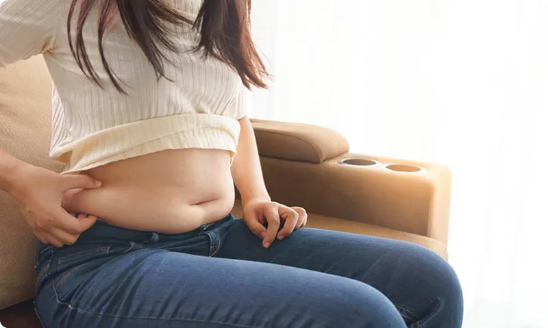 Person sitting on a couch wearing a white top and blue jeans