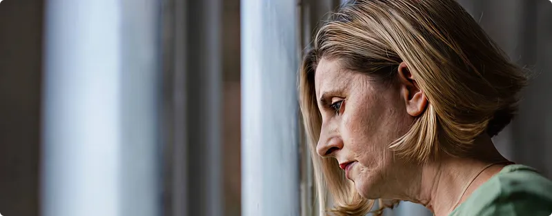 Woman looking out a window with a contemplative expression