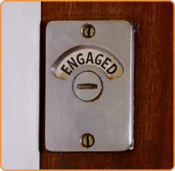 Metal switch plate with 'ENGAGED' label on a wooden background
