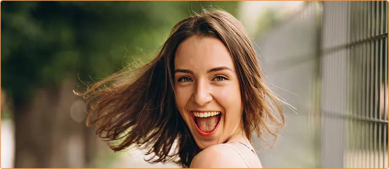 Woman with brown hair laughing outdoors