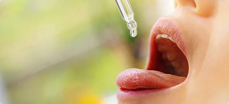 Person applying a dropper of liquid to their lips