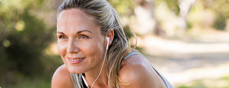 Woman with earphones outdoors, smiling