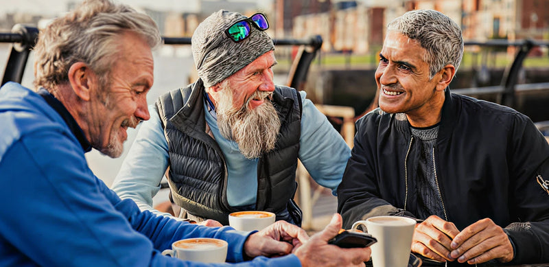 Three men sitting together, enjoying coffee and conversation outdoors.