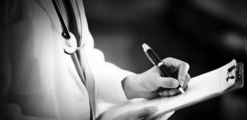 Doctor writing on a clipboard with a stethoscope around their neck.